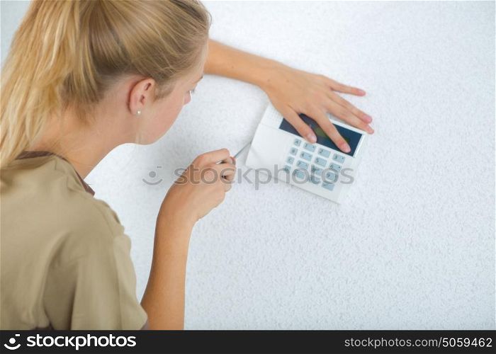 woman fitting an airconditioning screen at the wall