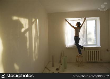Woman fitting curtains in new apartment