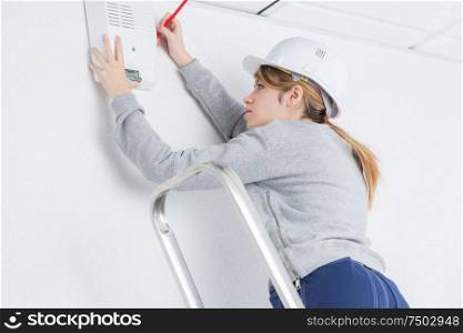 Woman fitting electrical appliance to wall