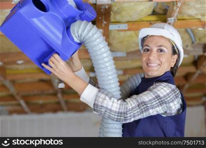 woman fixing a ventilation box indoors