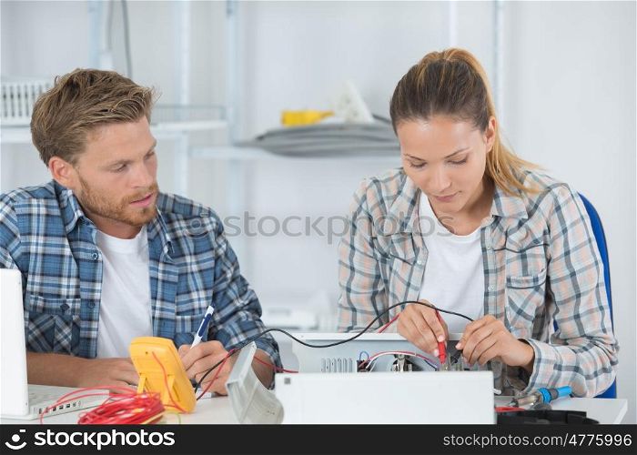 woman fixing computer with a man helping her