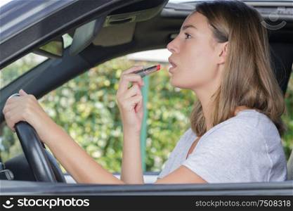 woman fixing make up in a car
