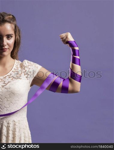 woman flexing her arm with ribbon suppport feminism