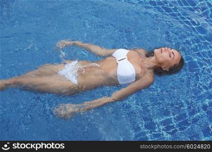 Woman floating in pool. Close up view of an attractive young woman floating in swimming pool