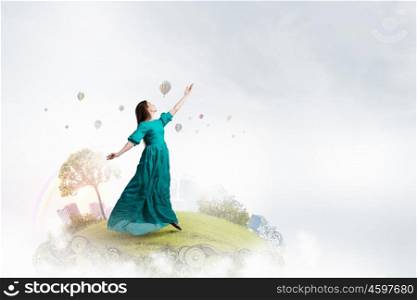 Woman floating in sky. Elegant woman in green long dress floating in sky