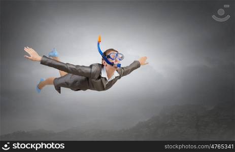 Woman floating in sky. Young businesswoman in suit and diving mask flying in sky