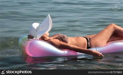 woman floating on inflatable mattress in the sea
