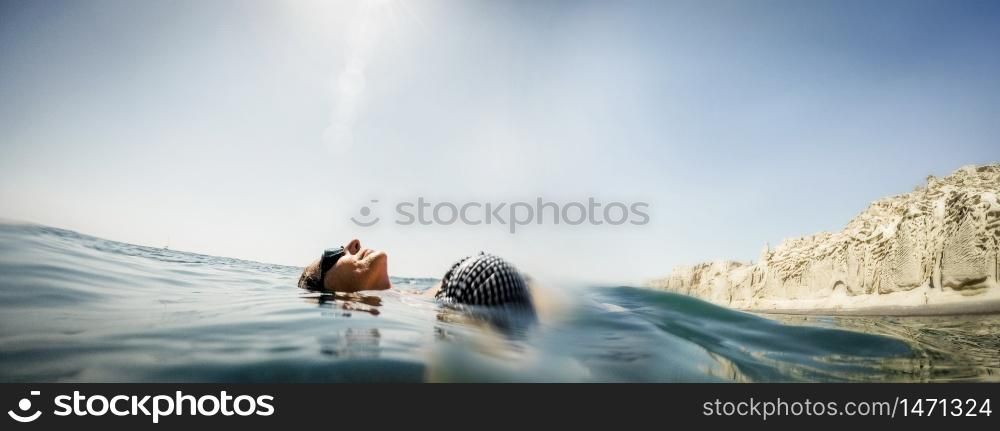 woman floating on water cliffs in background summer holiday