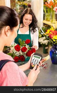 Woman florist selling flowers customer paying credit card red roses