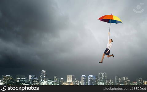 Woman fly on umbrella. Young businesswoman flying high in sky on umbrella