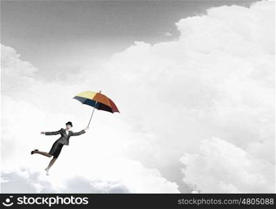 Woman flying on umbrella. Young businesswoman in suit and hat with colorful umbrella