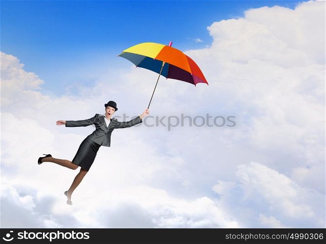 Woman flying on umbrella. Young businesswoman in suit and hat with colorful umbrella