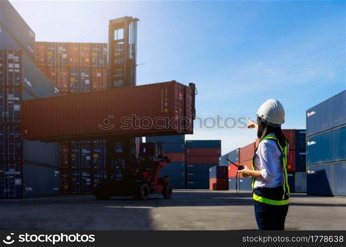 Woman Foreman control loading Containers box from Cargo freight ship for import export.