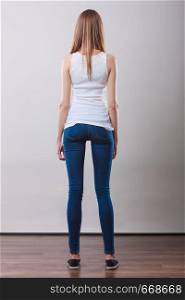 Woman full length in denim trousers white blank top back view