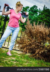 Woman gardener removing withered dried thuja tree from her backyard. Yard work around the house. Woman removing dried thuja tree from backyard