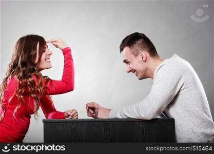 Woman gesturing with finger on her head sitting in front of man. Are you crazy? Girl mocking laughing at man.. Girl gesturing with finger sitting in front of man