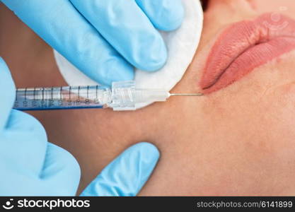 woman gets injection in her lips. Closeup of woman gets injection in her lips