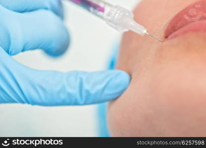 woman gets injection in her lips. Closeup of woman gets injection in her lips