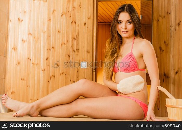 Woman girl in spa sauna relaxing massaging skin with exfoliating glove. Skincare concept.. Woman in sauna with exfoliating glove. Skincare.