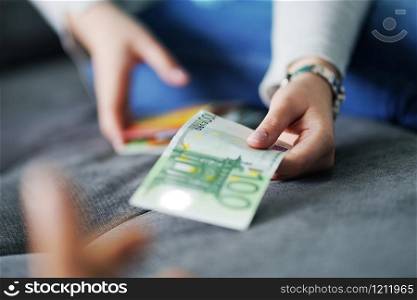 Woman giving 100 Euro banknote to her husband on the bed at home