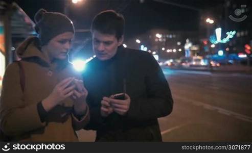 Woman giving phone number to a man. They standing by the road in the city at night