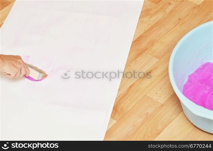 woman gluing wallpaper on the floor