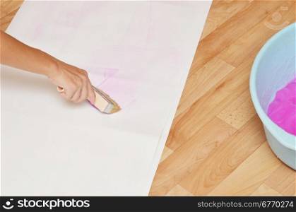 woman gluing wallpaper on the floor