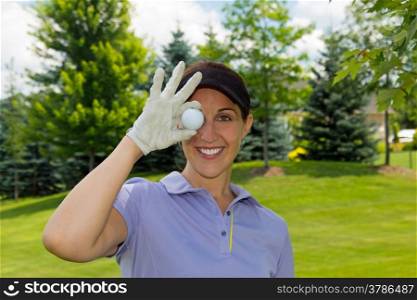 Woman golfer holding a golf ball over her eye