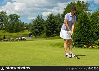 Woman golfer putting the golf ball on the green