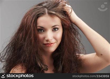 woman grabbing her tangled hair in frustration on grey background