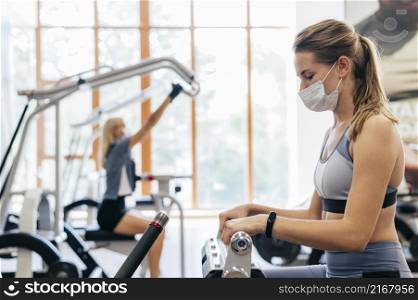 woman gym using equipment with medical mask