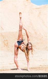 woman gymnast doing exercises on sand in bikini