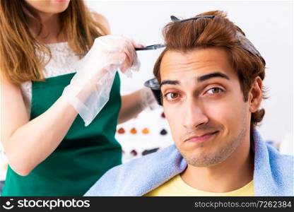 Woman hairdresser applying dye to man hair. The woman hairdresser applying dye to man hair
