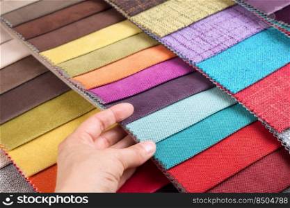 Woman hand chooses s&les of colored fabric on table close up. Woman hand chooses s&les of colored tissue