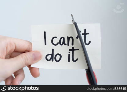 "Woman hand cutting paper note with scissors to remove T word "I can't do it" isolated on white background. Positive attitude, self belief and motivation concept."