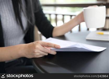woman hand drinking coffee with business paper