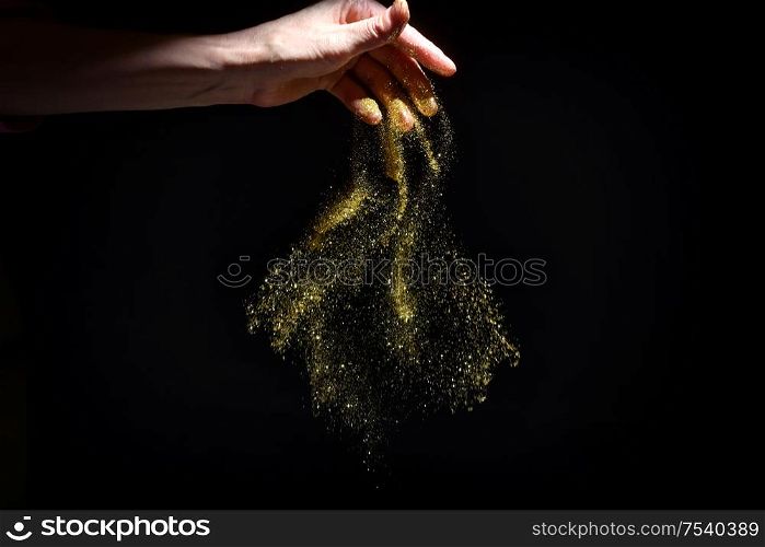 Woman Hand Drop Glitter Sparkles on Black Background