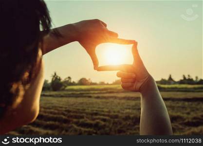 woman hand framing view distant over sunset. business concept