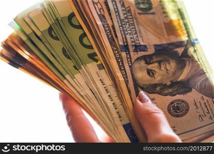 Woman hand giving money like bribe or tips isolated on white background. EURO and USD currency banknotes close up. Reward for hard work, inflation, finance and business concept