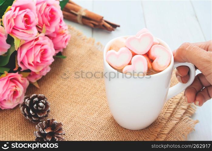 Woman hand holding a hot chocolate with pink marshmallows on top. Love, beauty, Valentine's Day