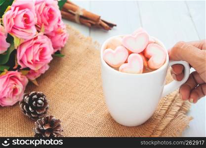 Woman hand holding a hot chocolate with pink marshmallows on top. Love, beauty, Valentine's Day