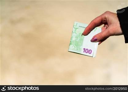 Woman hand holding and giving money. World money concept, close up of 100 EURO banknote, photo of EUR currency isolated. Hand holding money, EURO currency