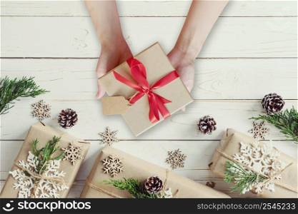 Woman hand holding Christmas presents gift box on a wooden table background