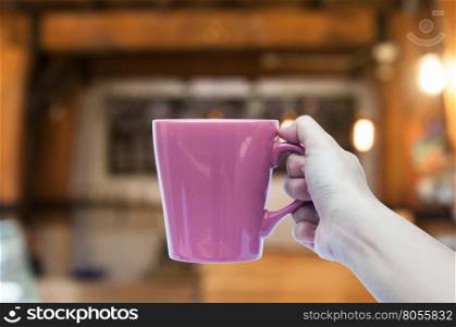 Woman hand holding coffee cup in coffee shop blurred abstract background