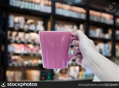 Woman hand holding coffee cup on blurred background, stock photo