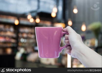 Woman hand holding coffee cup on coffee shop blurred background, stock photo