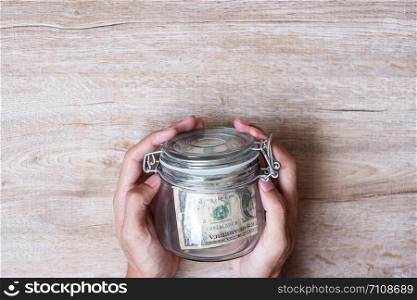 Woman hand holding coin money in glass jar. world saving day, business, investment, retirement planning, finance concept
