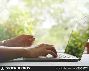 woman hand holding credit card and shopping online in black friday sales on computer laptop with bokeh background, copy space