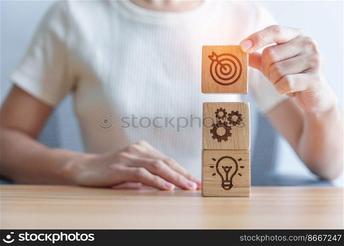 Woman hand holding dartboard above Gear and Lightbulb icon block. business planning process, goal, strategy, target, mission, action, objective, teamwork and idea concept