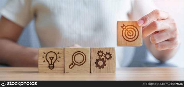 Woman hand holding dartboard above Gear, magnifying and Lightbulb icon block. business planning process, goal, strategy, target, mission, action, research, teamwork and idea concept